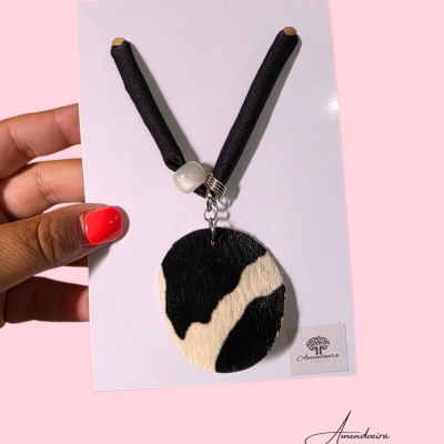 Colar preto e branco com padrão de pele em cartão branco e fundo rosa.