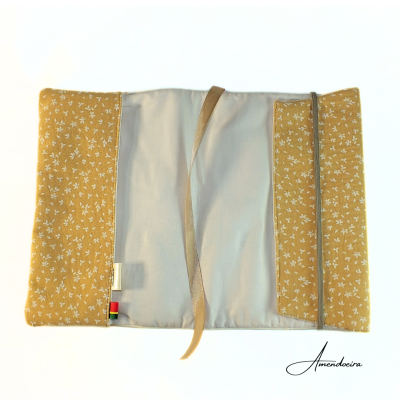 Estojo tecido cinza claro e amarelo floral, com fita elástica e fita para amarrar sobre fundo branco