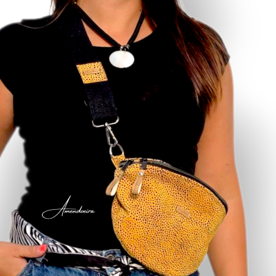 Bolsa amarela de padrão pontilhado com alça preta larga e roupa casual num ambiente neutro