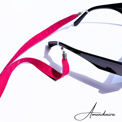 Óculos de sol pretos com fita vermelha ligados e assinatura Amendoeira