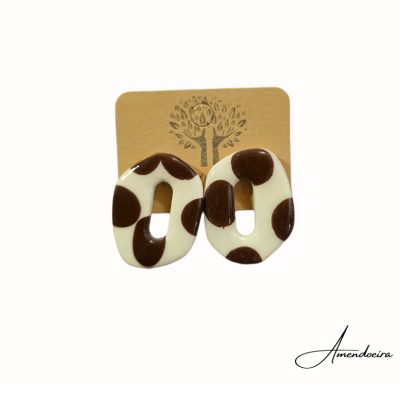 Brincos ovais creme com manchas castanho-escuras em cartão castanho com desenho de árvore