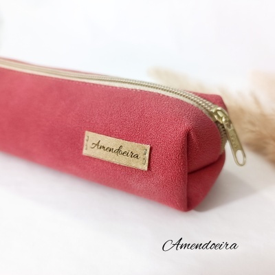 Estojo rosa com fecho dourado e etiqueta Amendoeira