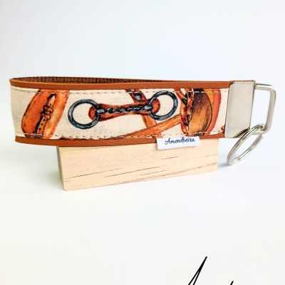 Coleira ajustável castanha e creme com padrão de acessórios e etiqueta 'Amendoeira'