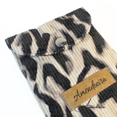 Estojo com padrão animal print e etiqueta Amendoeira.