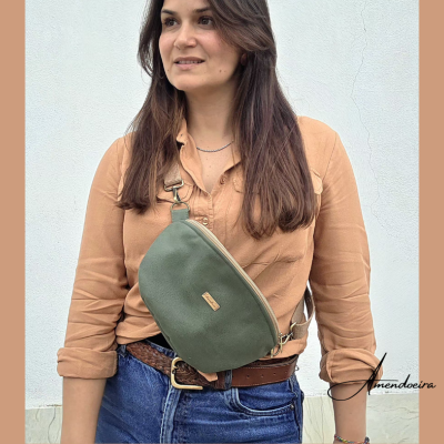 Mulher com camisa cáqui e bolsa verde tipo canguru com jeans em fundo branco
