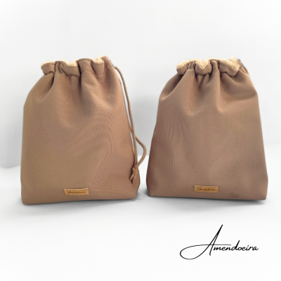 Duas bolsas bege de tecido com cordão e etiqueta frontal