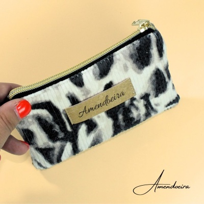 Carteira preta e branca com padrão animal e etiqueta Amendoeira