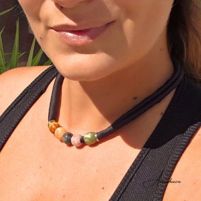 Colar com grandes contas coloridas em cordão preto, usado por mulher.