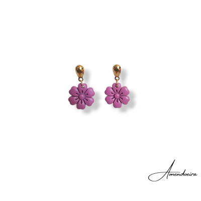 Brincos dourados com pendentes rosa em forma de flor sobre fundo branco