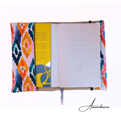 Protetor de livros em tecido com padrão geométrico colorido e livro aberto