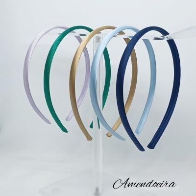 Conjunto de cinco tiaras coloridas em tecido expostas em suporte transparente