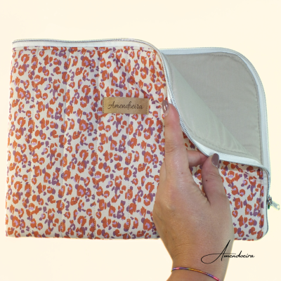 Necessaire com padrão animal print em tons de bege, laranja e castanho com etiqueta 'Amendoeira' e interior cinzento