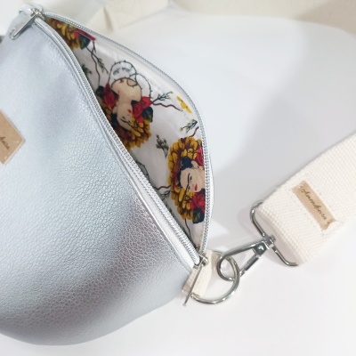 Bolsa tipo pochete prateada com alça bege e forro floral