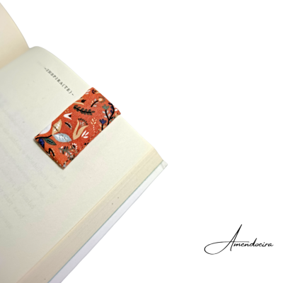 Marcador de página em tecido laranja com padrão floral num livro aberto