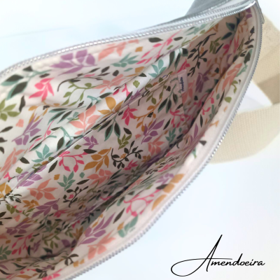 Interior de bolsa aberta com padrão floral colorido e fecho prateado