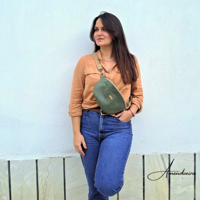 Mulher com camisa castanha, jeans azul e bolsa tiracolo verde