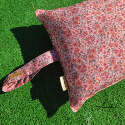 Almofada floral rosa com alça sobre relva artificial verde