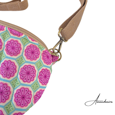 Bolsa estampada com padrão floral rosa e verde, alça castanha e fecho metálico