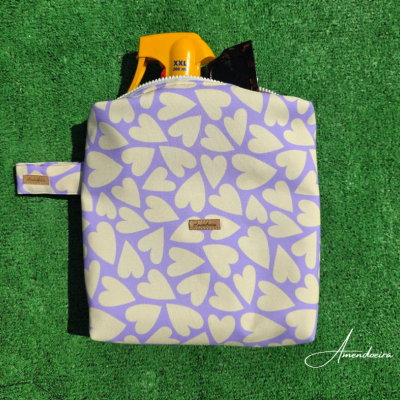 Mochila lilás com corações brancos sobre relva verde