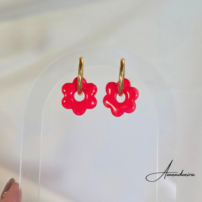 Brincos com argolas douradas e flores vermelhas num suporte transparente com Amendoeira