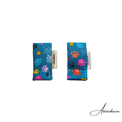 Duas presilhas de tecido azul com padrão colorido de patas e corações