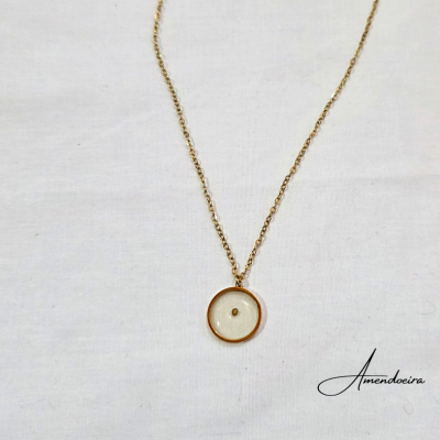 Colar dourado com pendente redondo transparente sobre fundo branco