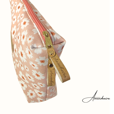 Necessaire rosa claro com padrão de flores brancas e puxadores de couro com gravação.