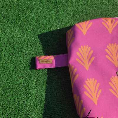 Bolsa rosa com padrão amarelo sobre relva artificial verde