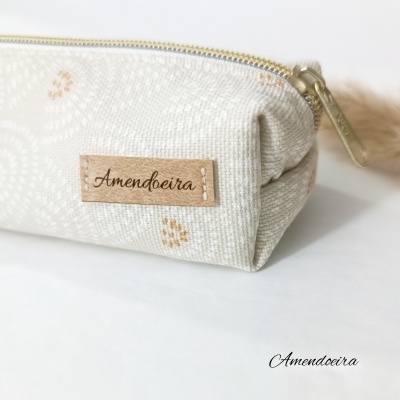 Estojo tecido bege floral com etiqueta Amendoeira e fecho dourado