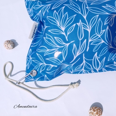 Almofada azul com padrões brancos e cordão branco com ilhó metálico