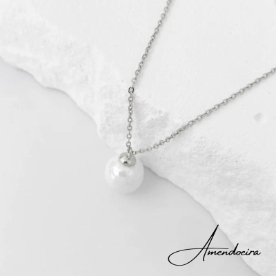 Colar prateado com pendente branco sobre superfície branca texturizada