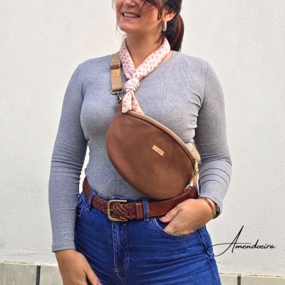 Mulher com bolsa castanha oval, lenço rosa e roupa casual azul e cinza