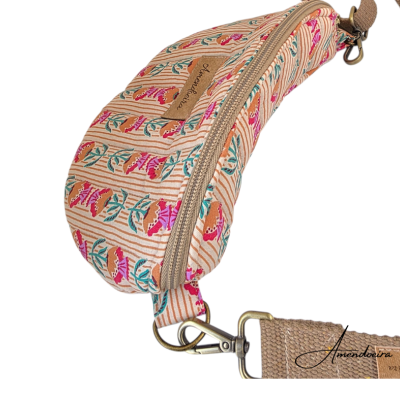 Bolsa tipo pochete com padrão floral em tecido, com fecho e alça ajustável.