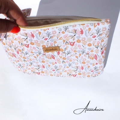 Estojo floral claro com fecho amarelo e etiqueta Amendoeira em fundo branco
