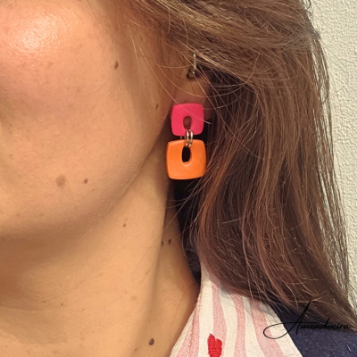 Brinco pendente rosa e laranja em mulher com camisa listrada