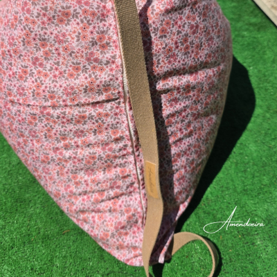 Coussin rose à motif floral avec sangle beige sur sol vert