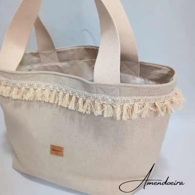 Mala bege clara de tecido com alças largas e franjas decorativas na borda superior