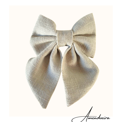 Laço de tecido bege texturizado com etiqueta 'Amendoeira'