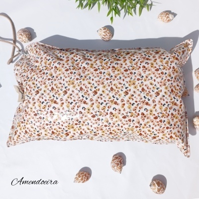 Travesseiro com capa floral e amêndoas sobre fundo branco