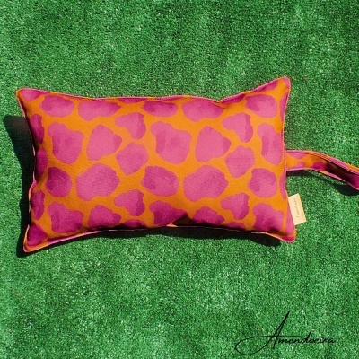 Almofada retangular rosa e laranja com padrão animal sobre relva verde