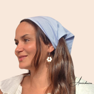 Lenço azul claro xadrez na cabeça de mulher com brinco de flor branca e roupa branca