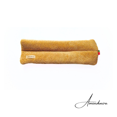 Travesseiro castanho retangular em tecido aveludado com etiqueta e fita colorida, sobre fundo branco