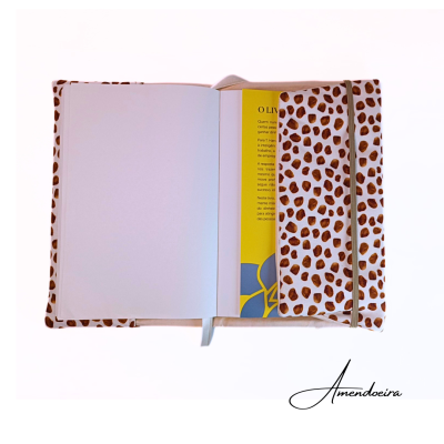 Caderno aberto com capa estampada padrão pintas castanhas e folhas internas visíveis