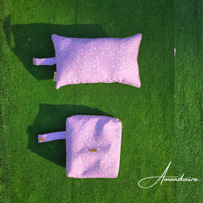 Duas almofadas cor de rosa com estrelas brancas sobre relva artificial verde.