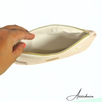 Bolsa creme com flores amarelas e fecho dourado aberta, vista interior