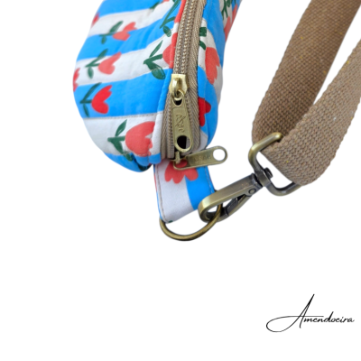 Bolsa colorida com padrão floral e fecho dourado, alça castanha com gancho metálico