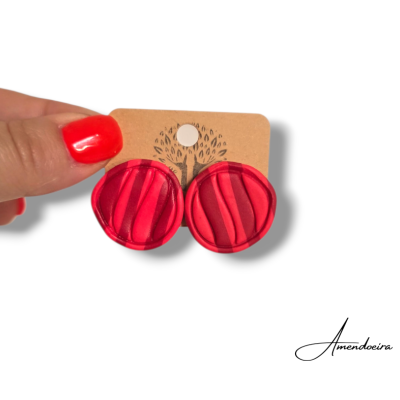 Brincos redondos de tecido vermelho em cartão castanho claro com desenho preto