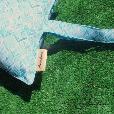 Almofada azul com padrão de folhas sobre relva artificial verde