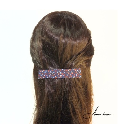 Clipe de cabelo azul escuro com padrão floral preso em cabelo castanho claro liso