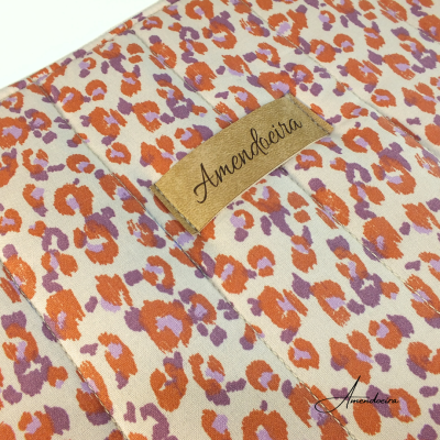 tecido estampado cor creme com manchas laranja e lilás e rótulo Amendoeira